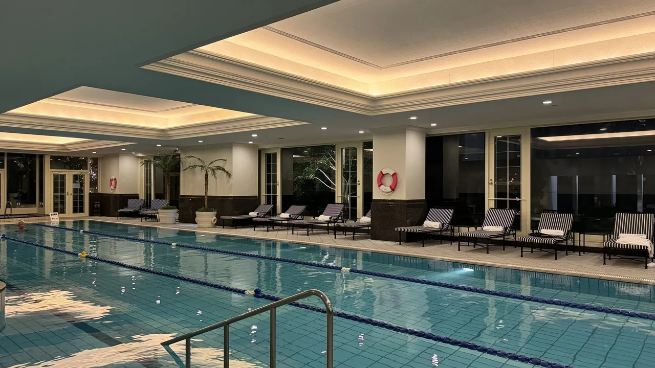Loungers along the pool hall below a lit ceiling