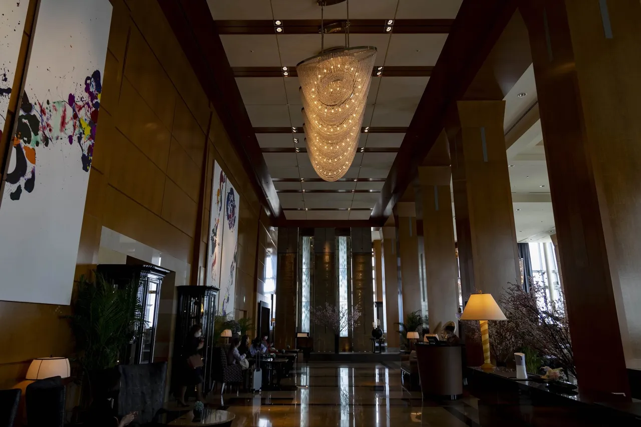 The long 45th-floor lobby hall with a crystal chandelier and abstract art