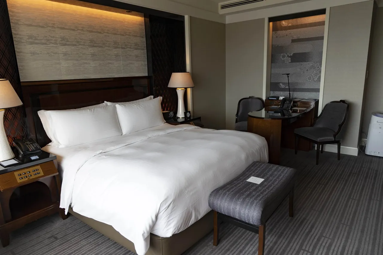 Our Skyline king room with white linen, a bench and a lit headboard panel
