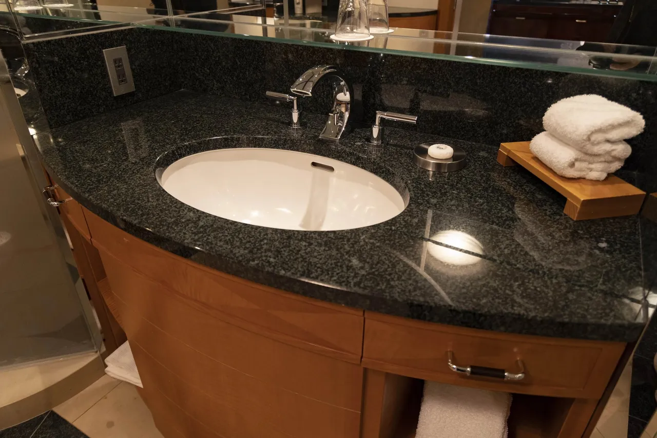 A granite vanity with an oval basin and folded towel