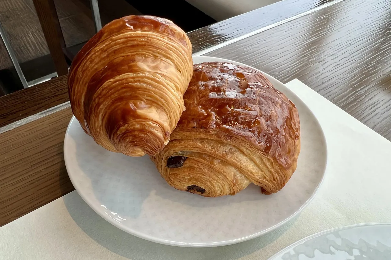 A croissant and pain au chocolat on a white plate