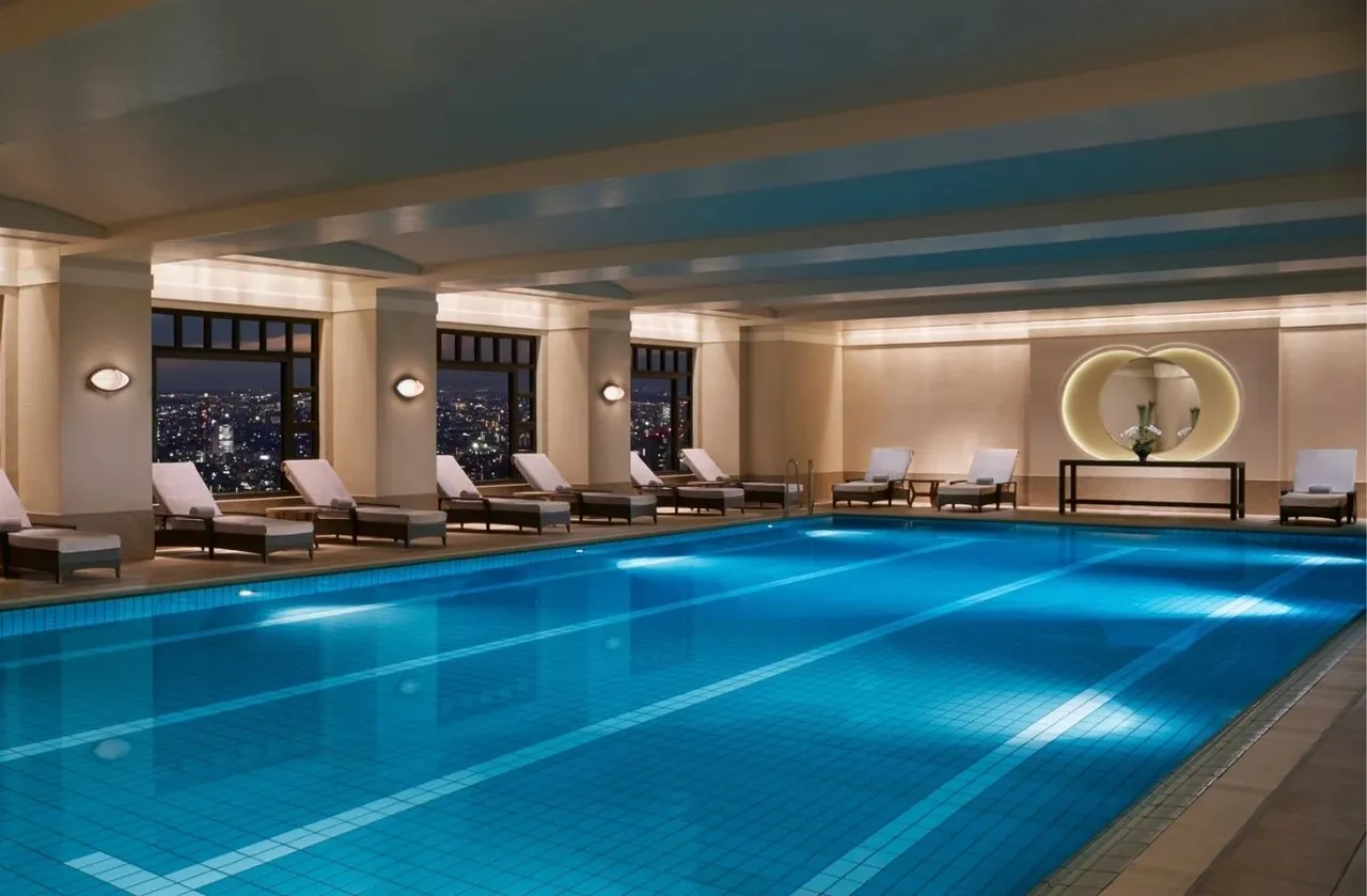 The indoor pool with loungers and city windows